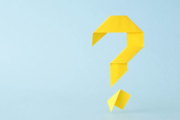 Folded yellow paper origami question mark on blue